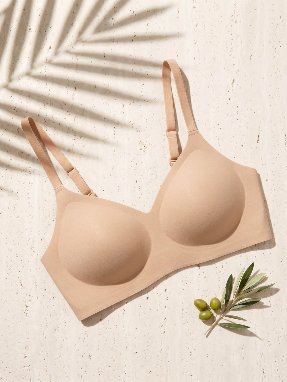 Kiri Charlotte Nude wireless bra on pale travertine with palm shadow