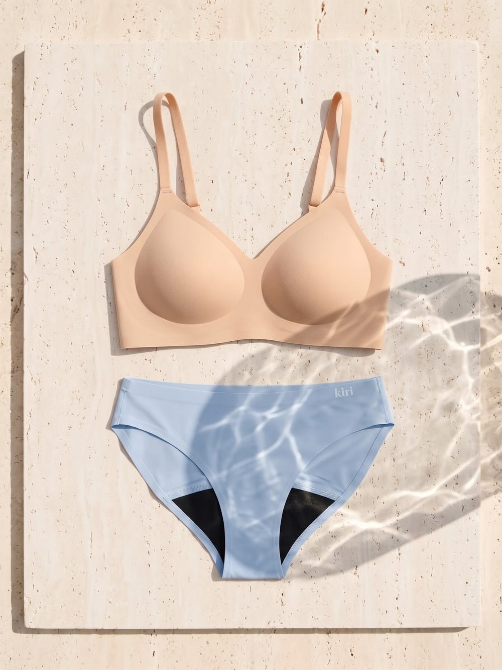 Kiri Charlotte Nude bra with Celeste Blue daywear period underwear as a set on travertine