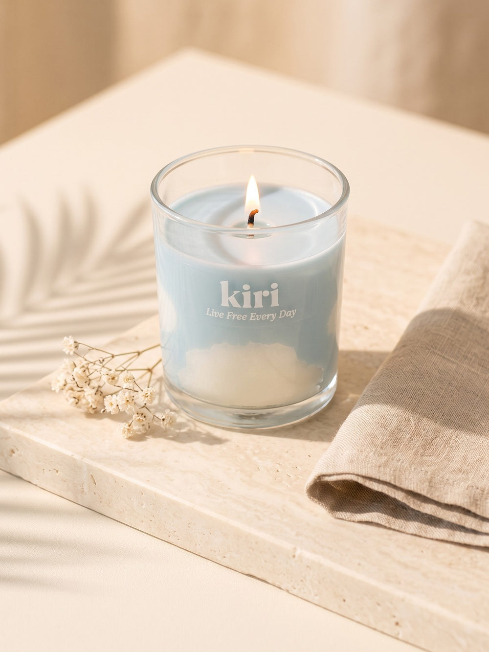 Kiri Live Free Every Day candle lit on pale travertine