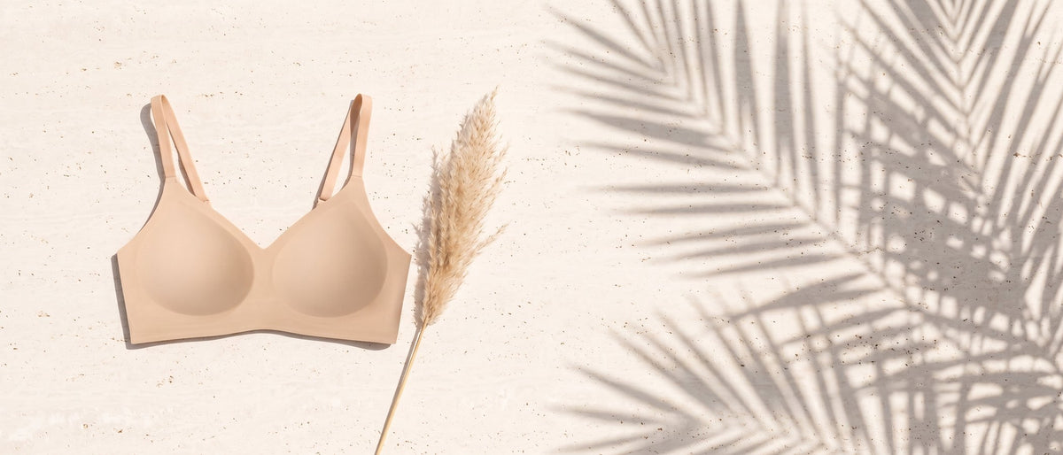 Kiri Charlotte Nude wireless bra on pale travertine with palm shadows